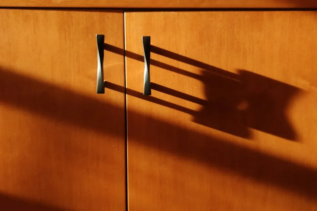 Cabinet doors with slim black bar pulls in raking light in a Mobile AL kitchen