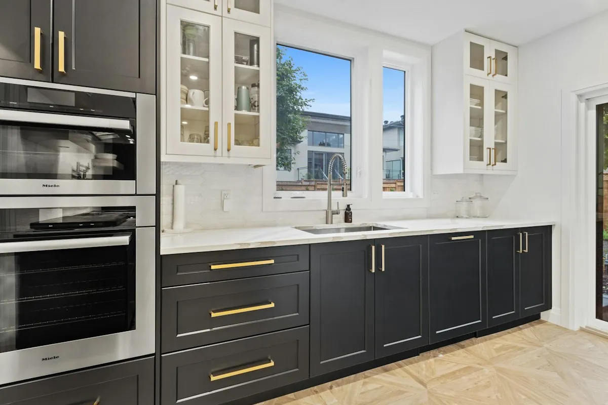 Two-tone custom kitchen cabinets with glass upper doors and brass pulls in a Mobile AL home