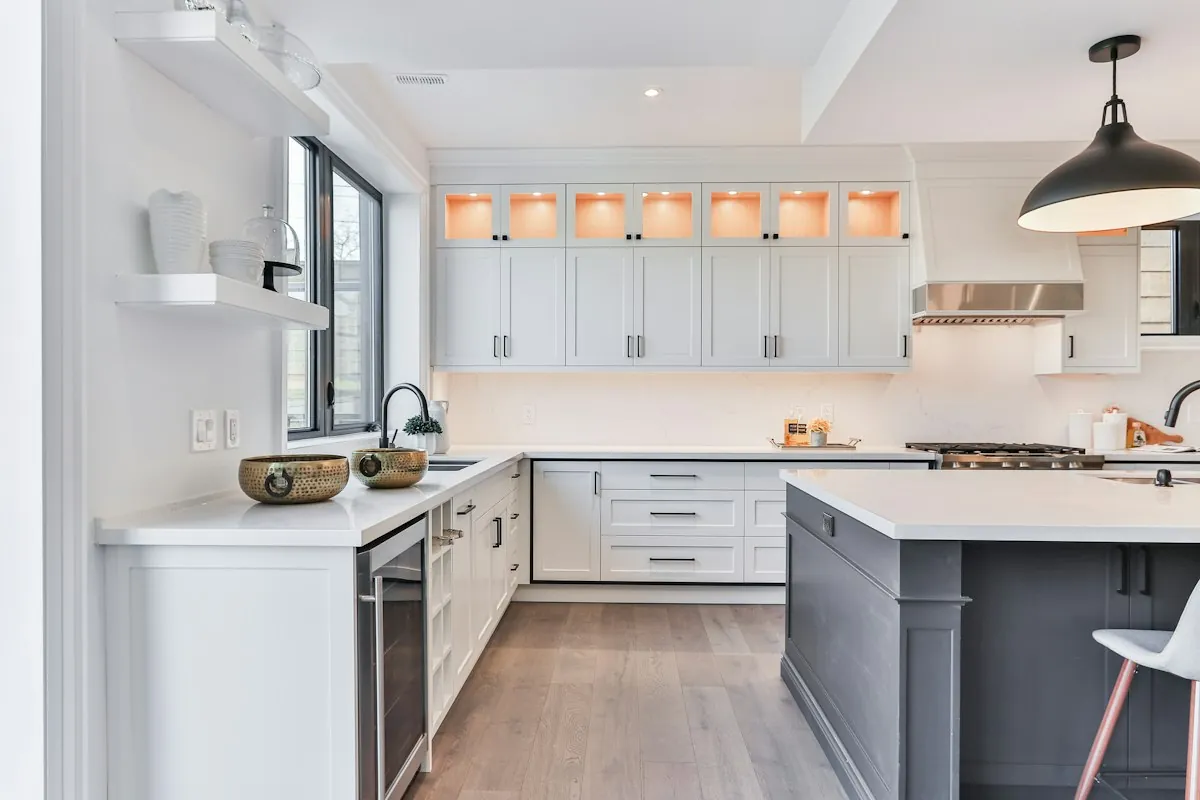 A grey painted kitchen island with white shaker perimeter cabinets in a Mobile AL kitchen