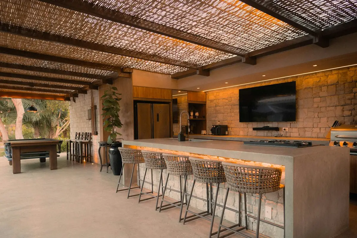 A covered outdoor kitchen island with a grill, concrete counter and bar stools, the format common in Mobile AL